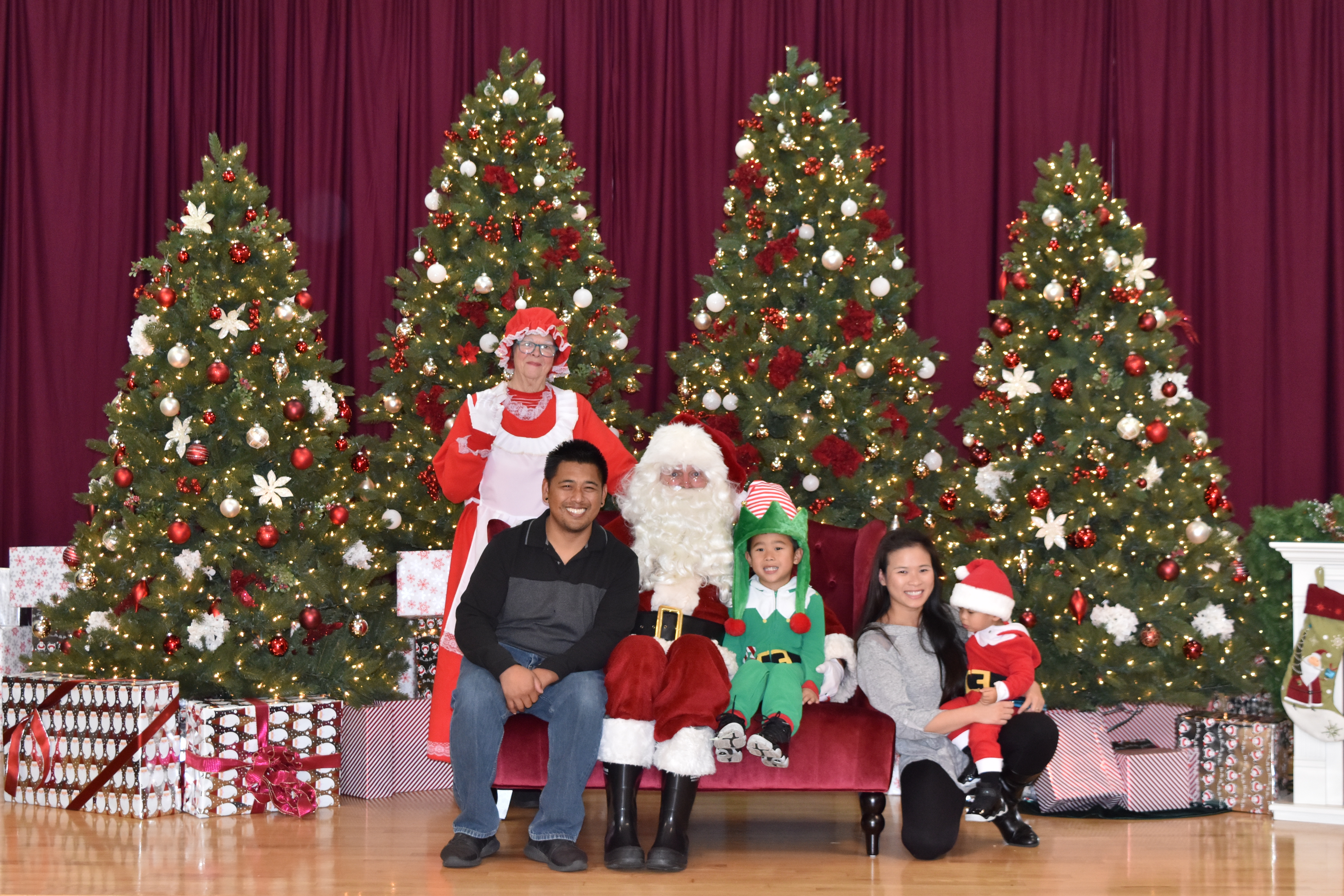 Family with Santa in front of holiday trees
